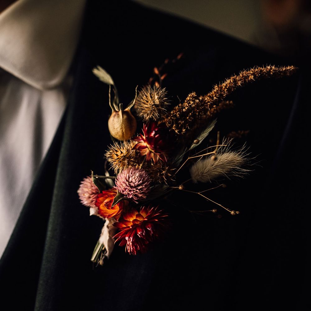 Groom in three piece suite, floral patterned tie and dried floral buttonhole before wedding in Cornwall with Halfpenny London Mayfair dress