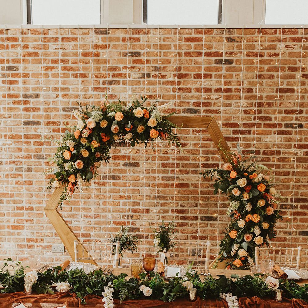 Hexagon wedding decor with orange flowers for backdrop to couples dinner