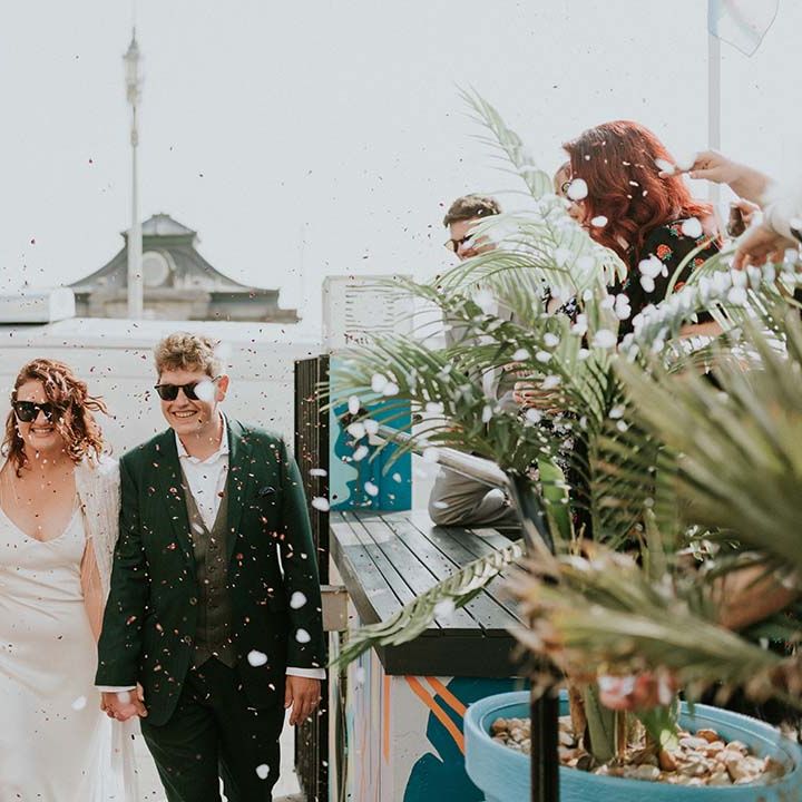 Bride & groom walk through confetti whilst wearing sunglasses on their wedding day