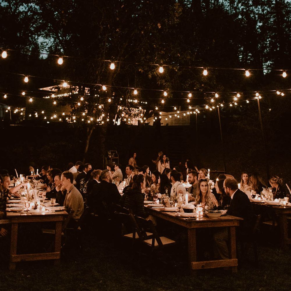 Guests gather outdoors for reception surrounded by candlelight 