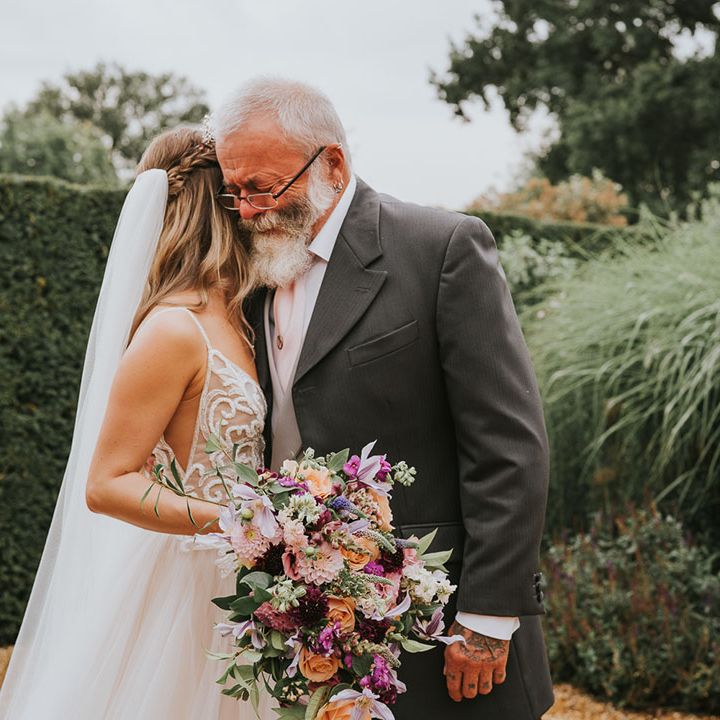 Bride holds brightly coloured wedding bouquet of purple, orange, pink and white flowers