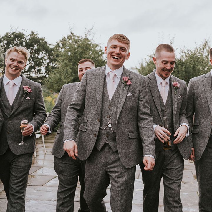 All of the groomsman together in matching grey tweed suits with pink ties and pink rose buttonholes