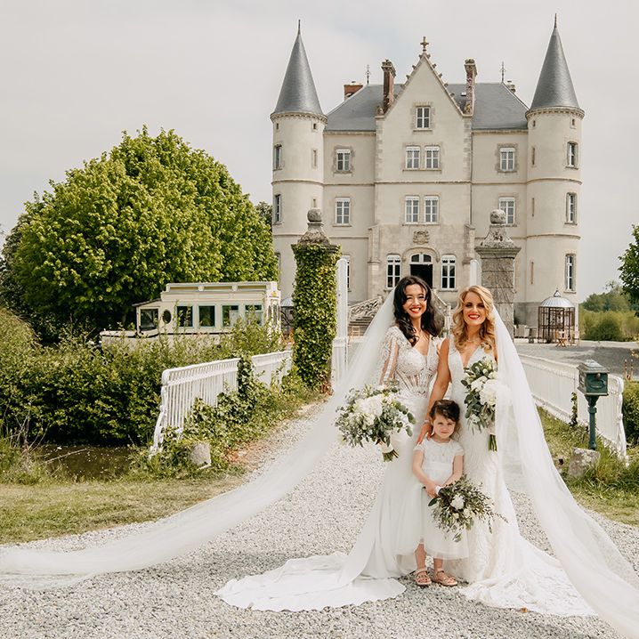 Brides pose with the flower girl all holding classic white wedding flower bouquets and pretty lace wedding dresses 