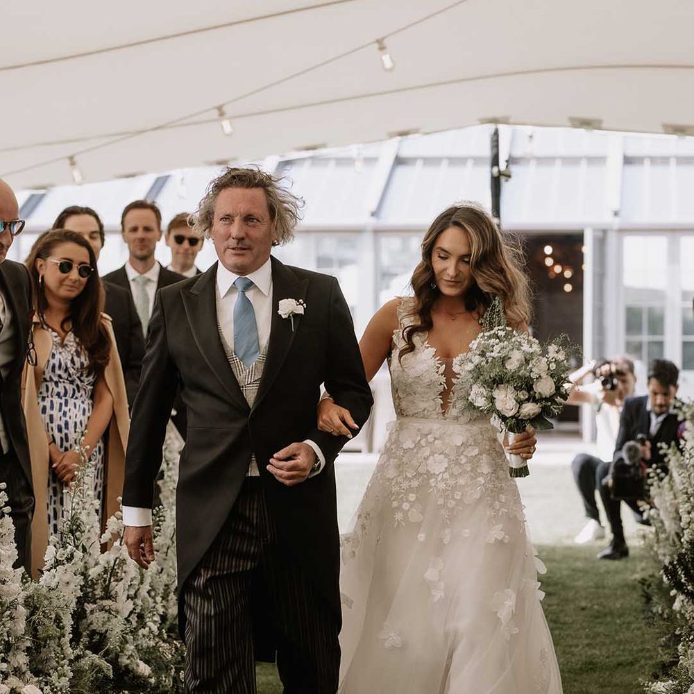 Father of the bride in striped trousers, morning suit jacket and plaid waistcoat walks the bride in Mira Zwillinger wedding dress down the aisle 