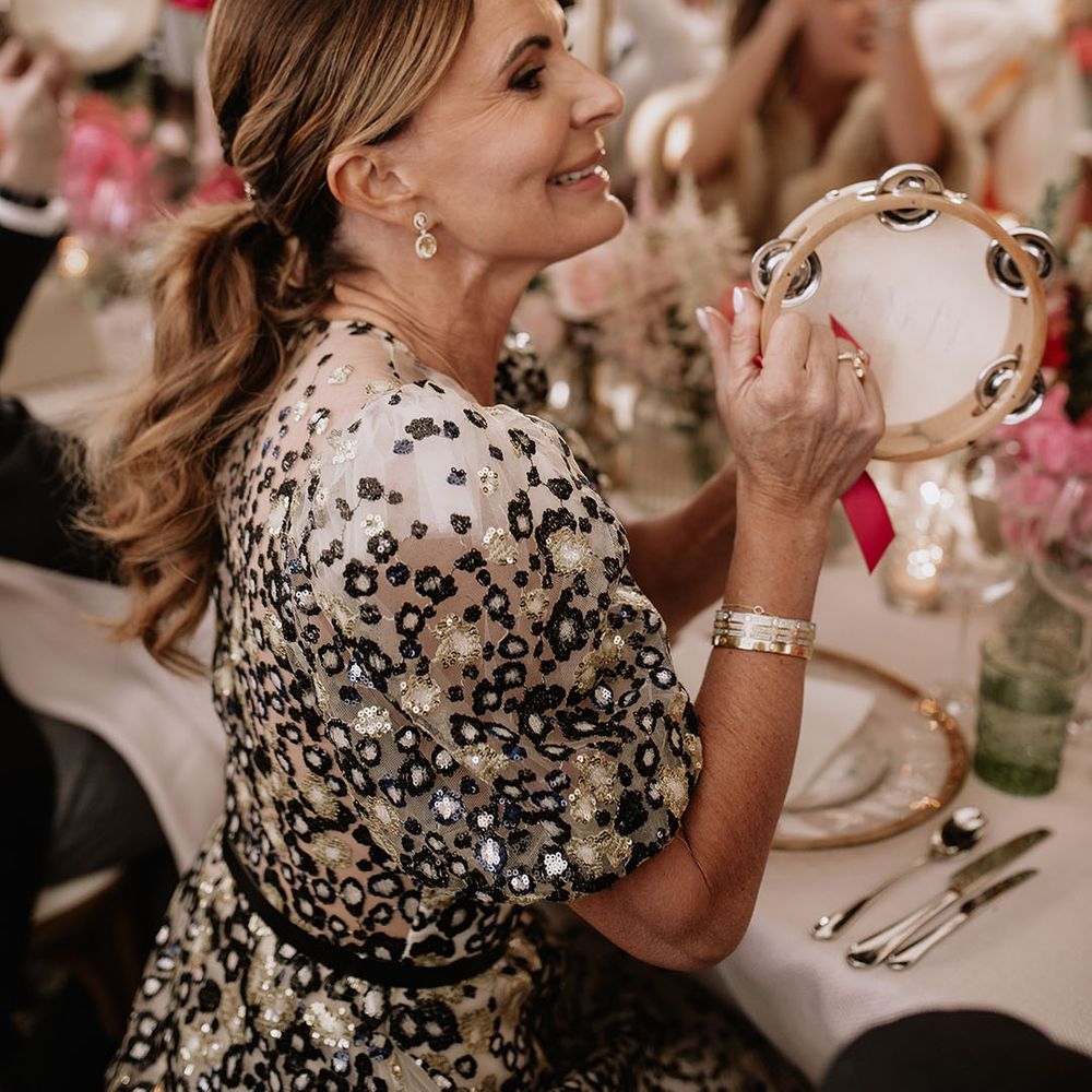 Wedding guest waves a tambourine to welcome the bride and groom into their wedding reception 