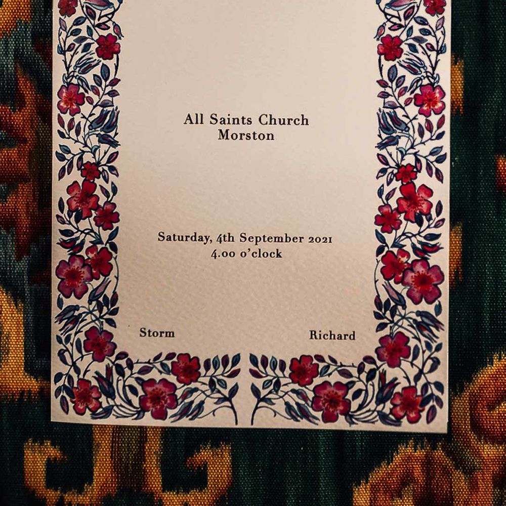 DIY cream wedding invitation with pink and red floral details around the sides