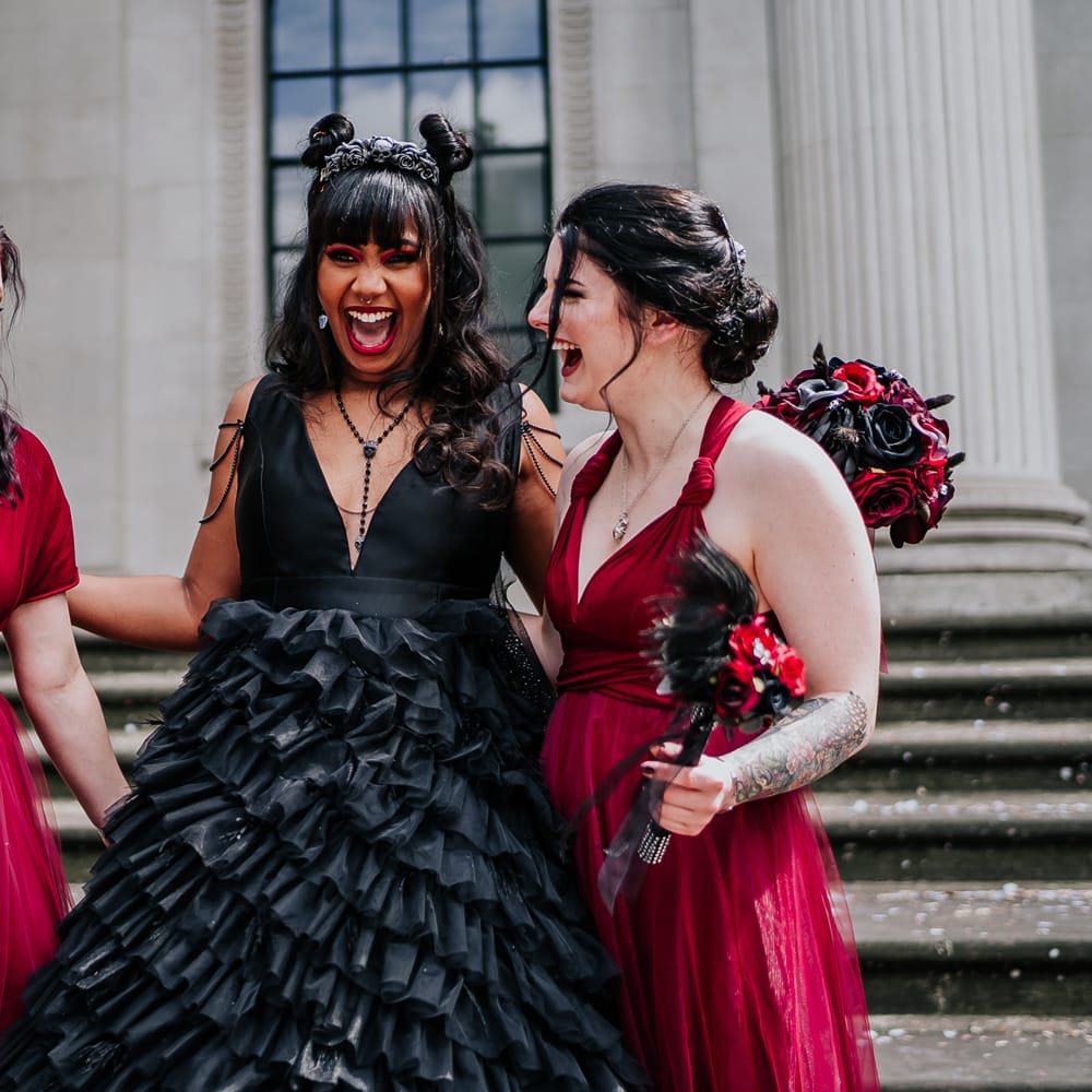 Bride stands with her bridesmaids who wear red bridesmaid dresses in different styling 