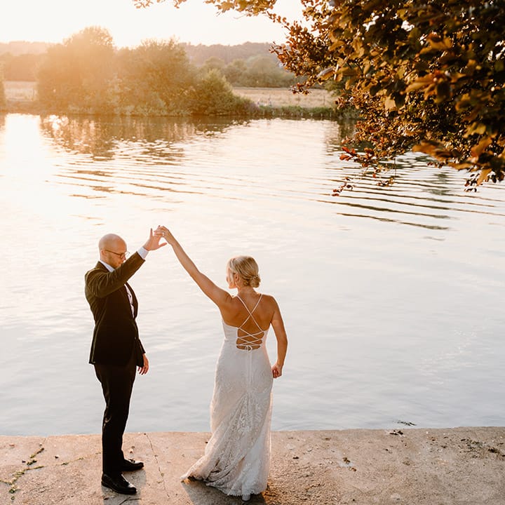 Bride & groom dance beside the River Thames on their wedding day during golden hour