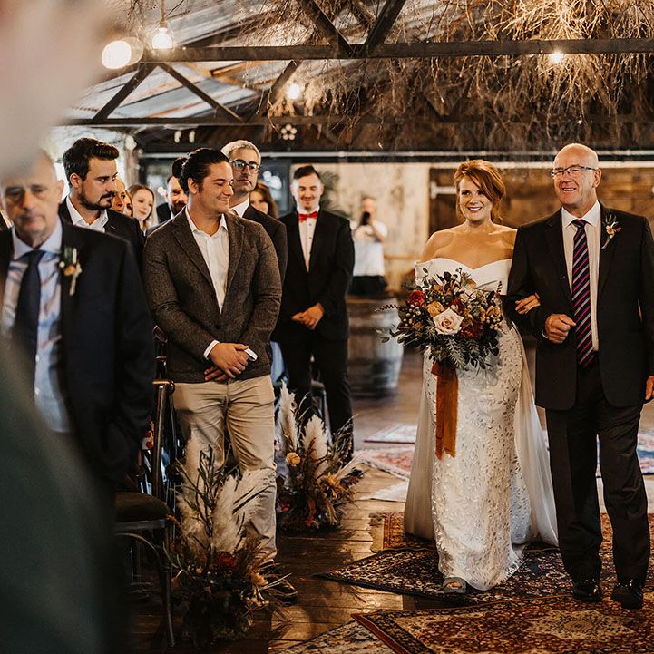 Bride in Love Spell wedding dress walks down the aisle across Moroccan styled carpets in The Dreys barn wedding venue 