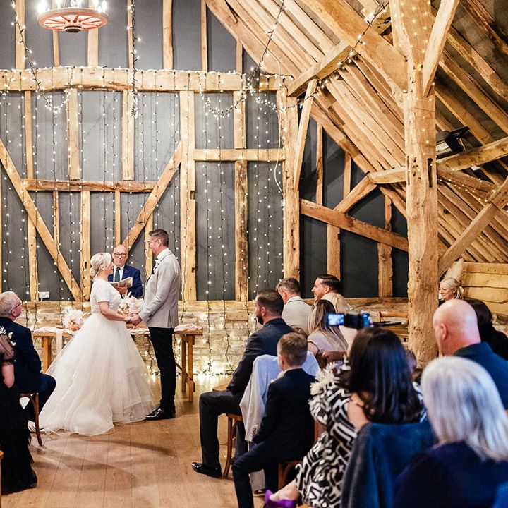 Fairy light Silchester Farm barn wedding ceremony room with the bride and groom standing at the altar 