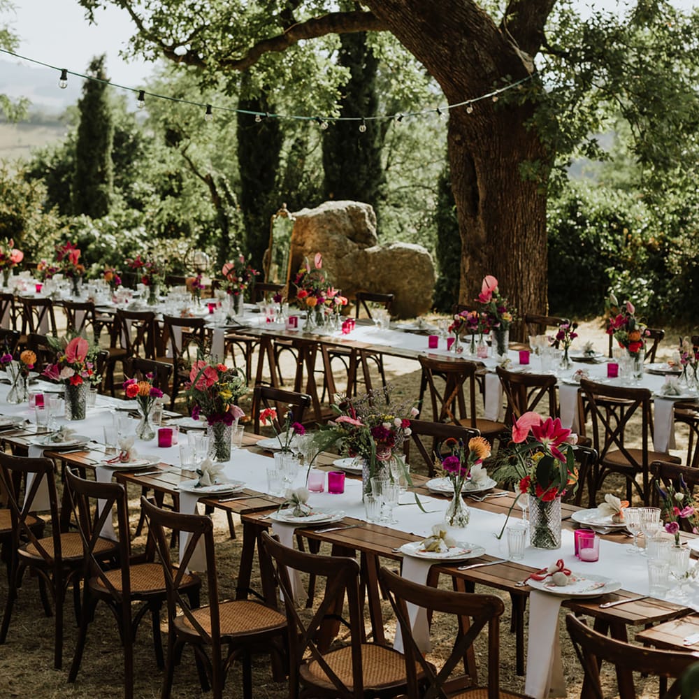 Banquet style tables at outdoor woodland wedding with rustic colourful tablescape