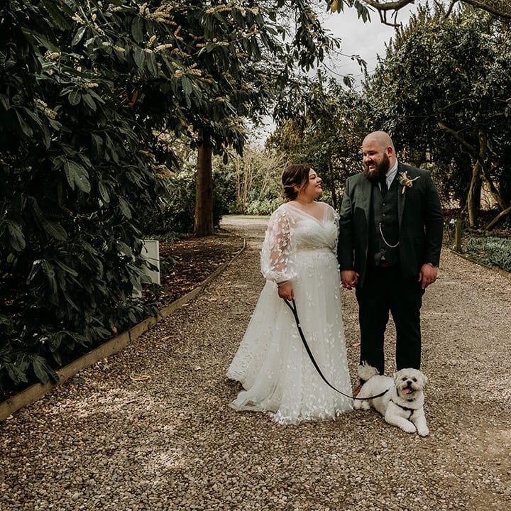 Groom in green tweed wedding suit with the bride and their pet dog 