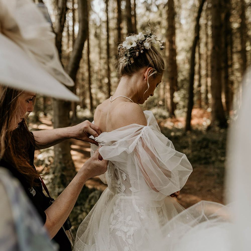 Bridesmaids help the bride put on her detachable wedding sleeves tog o with her Milla Nova wedding dress 