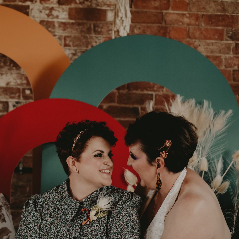 Two brides sitting at a 70s altar with dried flowers 