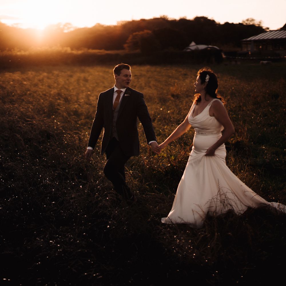 Bride & groom walk through the countryside during golden hour