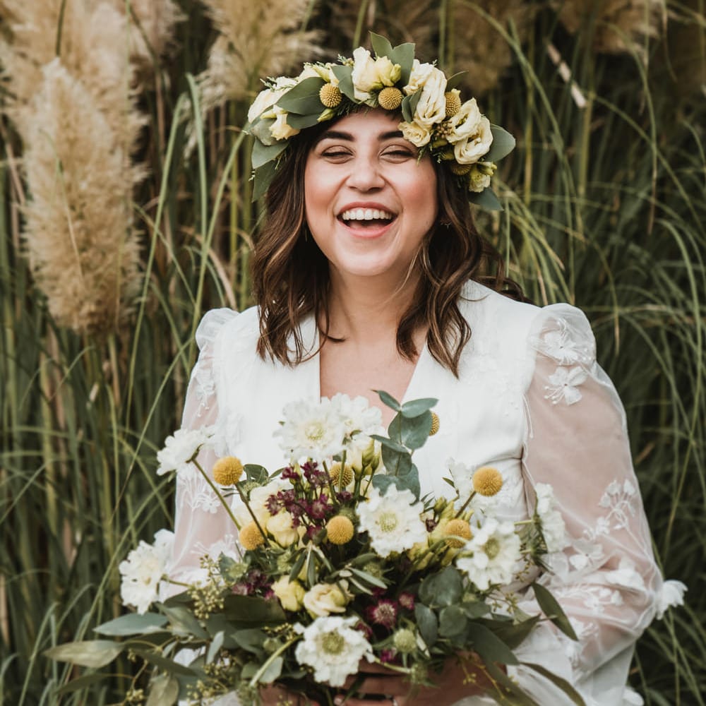 Smily boho bride in a flower crown holding her unstructured wedding bouquet 