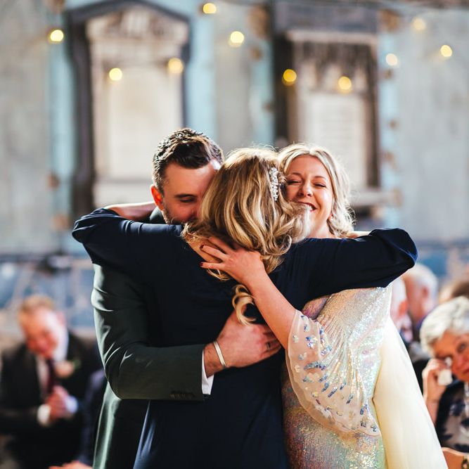 Bride & groom hug celebrant during wedding ceremony