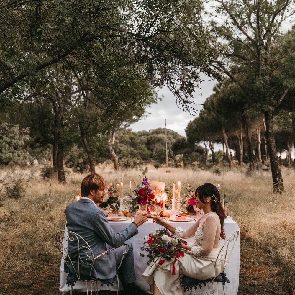 Bride & groom sit at colourful table with white linen cloth