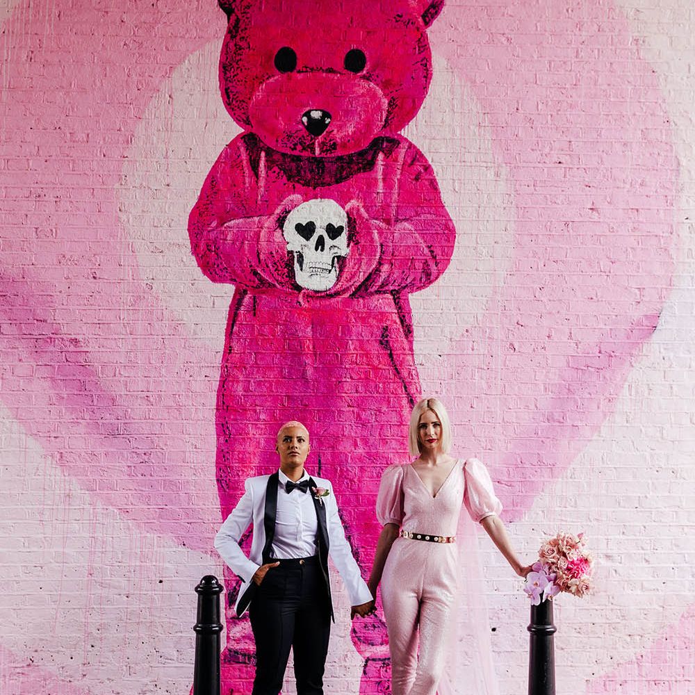 Alternative bride and bride standing in front of a pink teddy graffiti wall in Shoreditch 