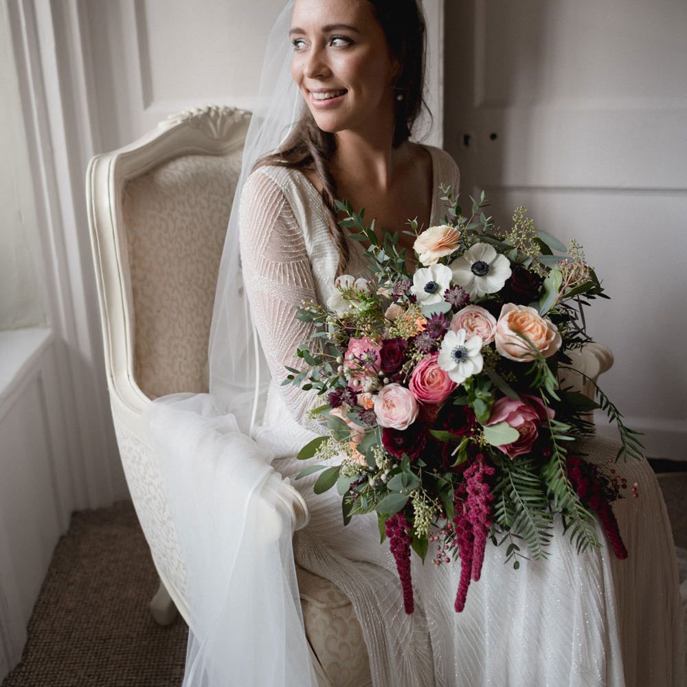 Bride in an embellished Eliza Jane Howell wedding dress holding a peach, pink and white wedding bouquet with roses and anemones 