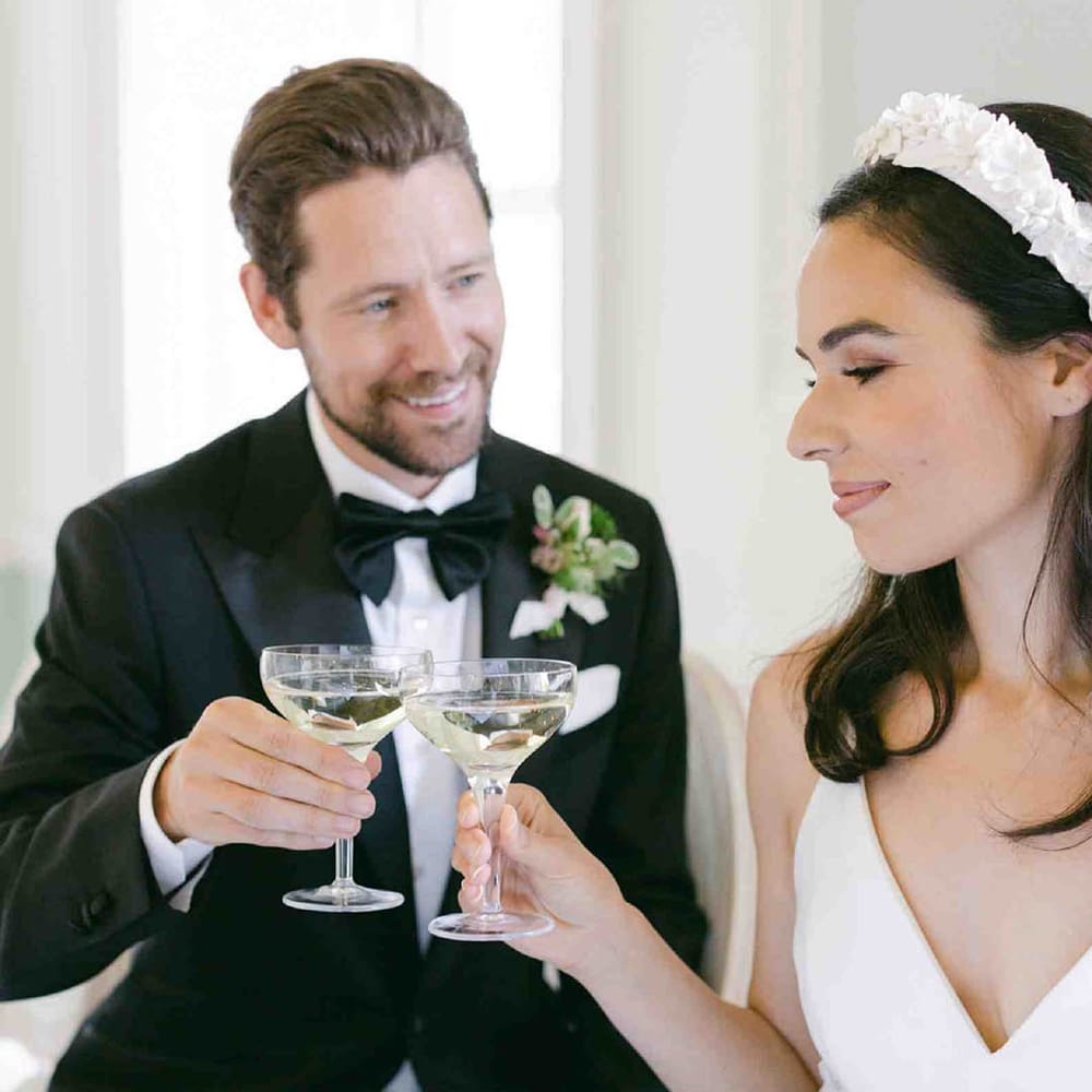 Bride in an applique headband toasting champagne glasses with her groom in a Tuxedo at Botley's Mansion 