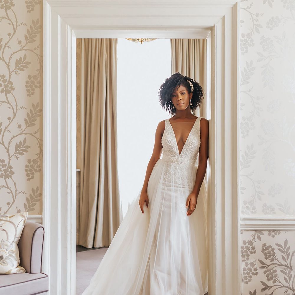 Beautiful black bride in a plunging neckline wedding dress with tulle skirt with naturally curly hair styled with a hair comb 