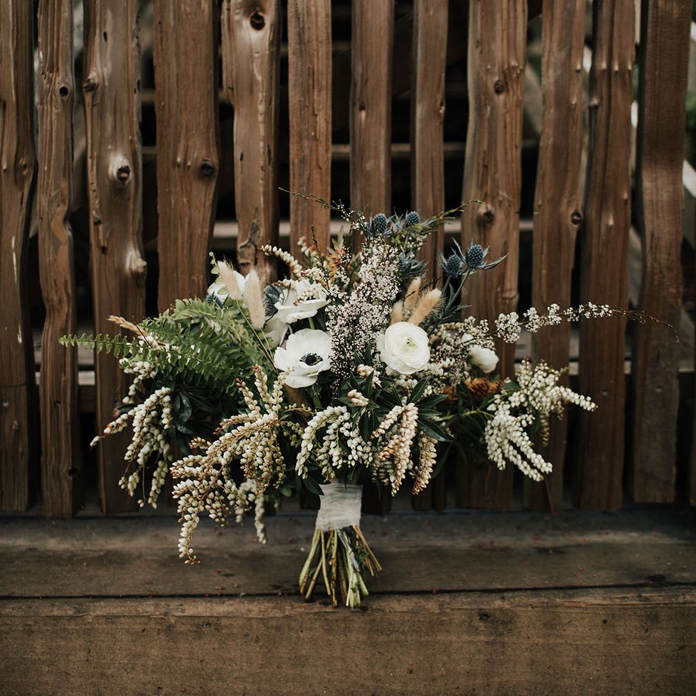 Natural wedding bouquet with anemones, snowdrops, foliage and dried grasses