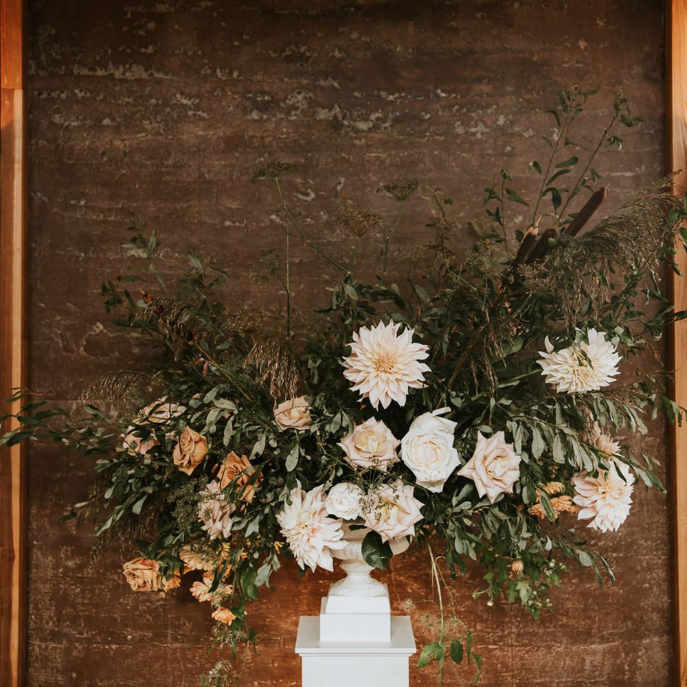 Roses, dahlias and foliage wedding flower arrangement on a plinth
