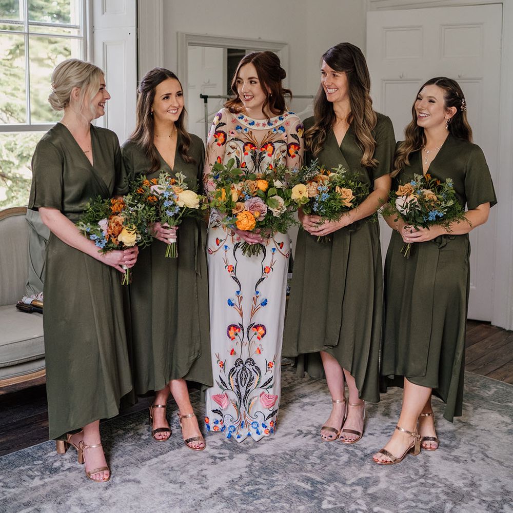 Bridesmaids in olive green wrap dresses and yellow and blue bouquets with bride in colourful wedding dress