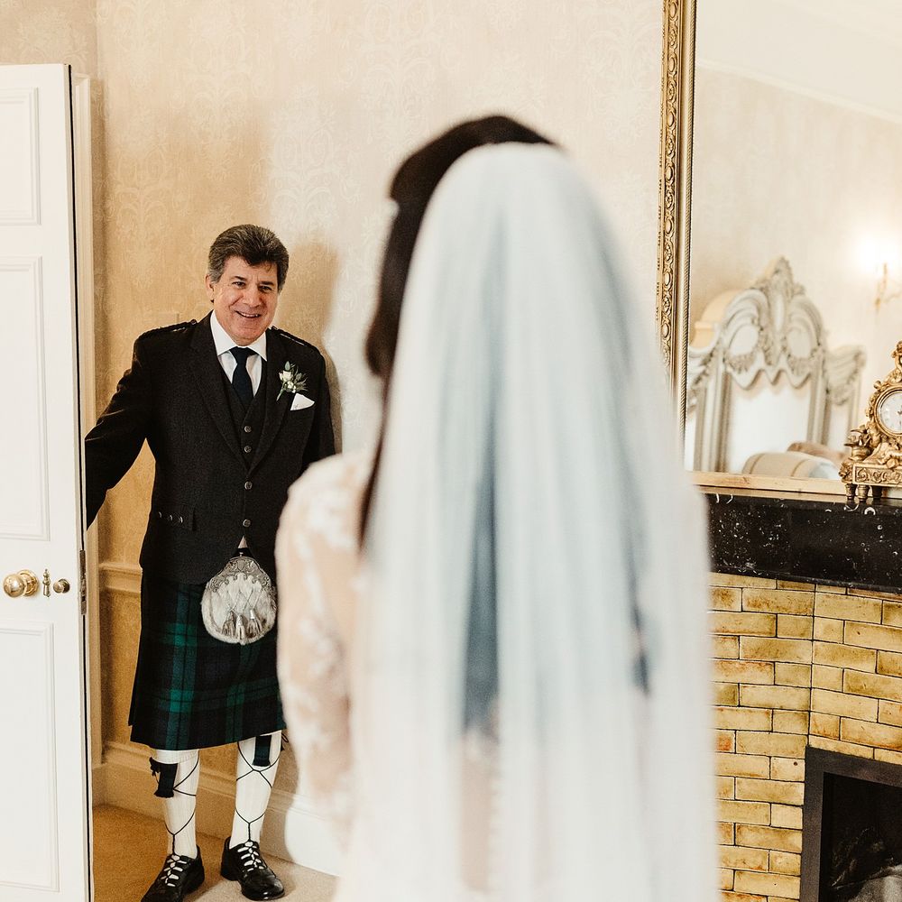 Brides father who wears tartan kilt sees his daughter for the first time who wears floor length veil 