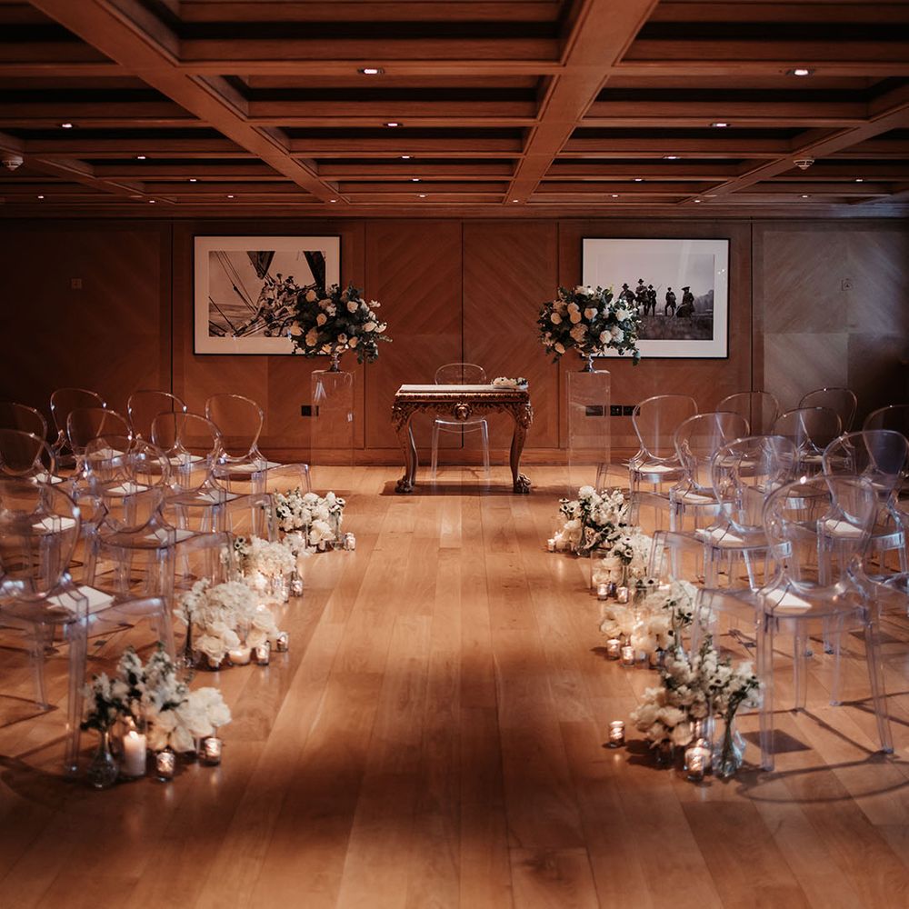 The Connaught hotel wedding ceremony venue with clear acrylic chairs with white sweet peas and anemone flower decor 