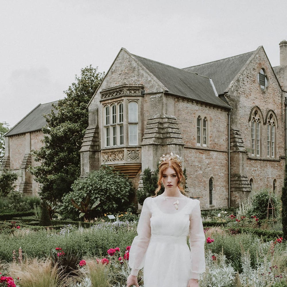 Bride with wearing matching gold leaf headpiece, necklace and cuff with a two layer wedding dress