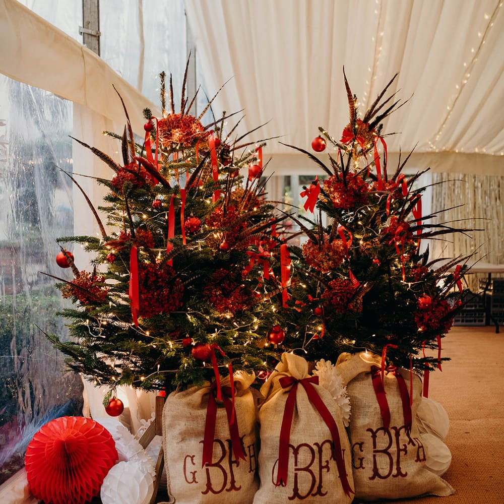 Christmas trees with baubles, decorations and fairy lights, and sacs with red DIY monogrammed initials on