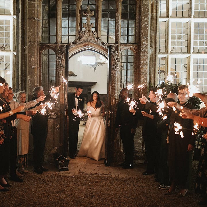 Wedding guests wave sparklers as the bride and groom exit from their reception 