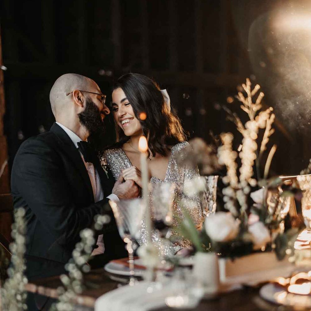 Bride and groom laughing together sat at rustic luxe wedding tablescape at Elmley Nature Reserve wedding venue 