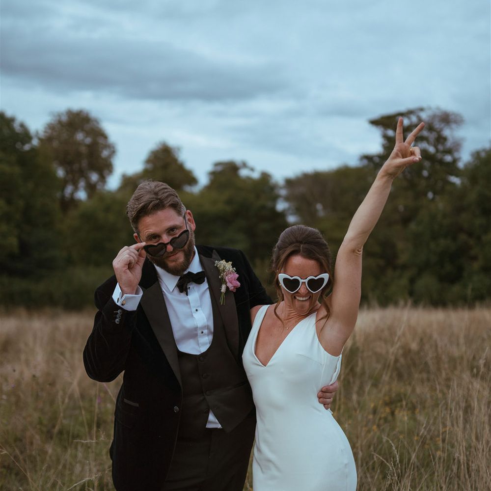 Bride in satin slip wedding dress by Made With Love with sunglasses posing with the groom for fun wedding photo