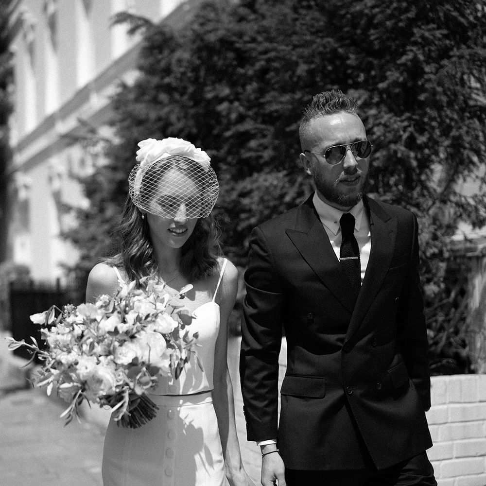 stylish couple at London city wedding in a black suit and bridal separates with headband and blush veil 