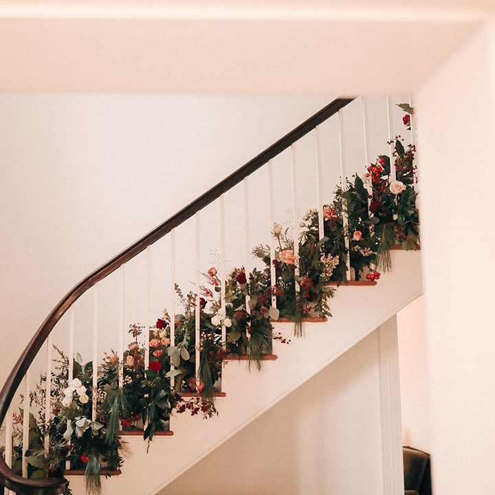 Festive red Christmas wedding flowers decorating the staircase at Aswarby Rectory in Lincolnshire 
