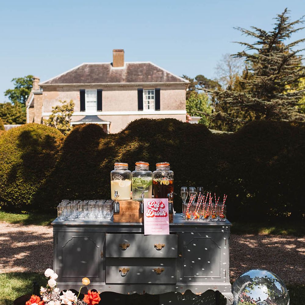 Outdoor hydration station for guests with large glass dispensers full of juice for wedding guests 