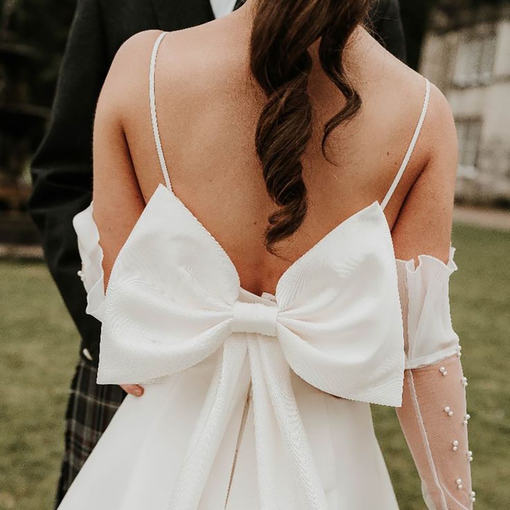Bride wearing an oversized bow wedding dress with large decorative bow on the back by Sophie Alexandria Photography