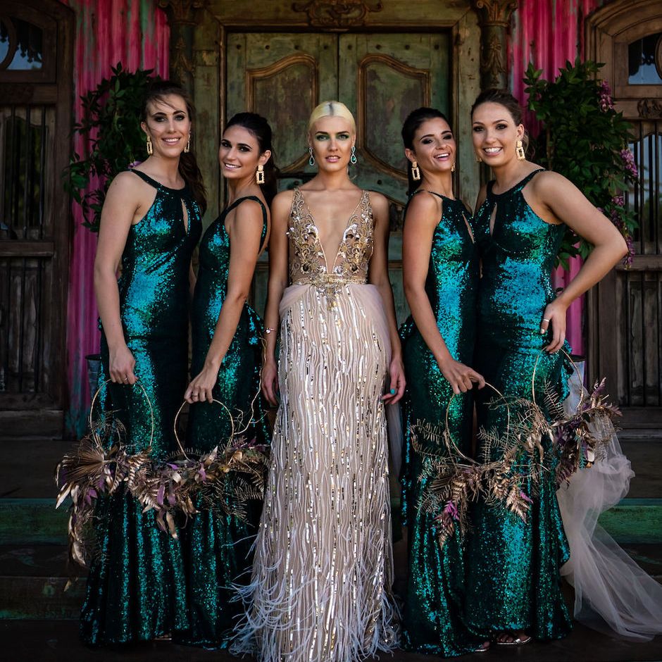 Bride in white and gold wedding dress with bridesmaids in sequin green dresses