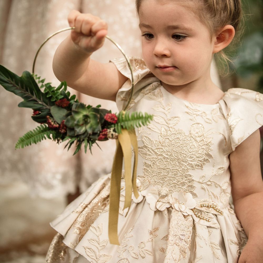 Little girl wears hair in messy bun surrounded by flowers