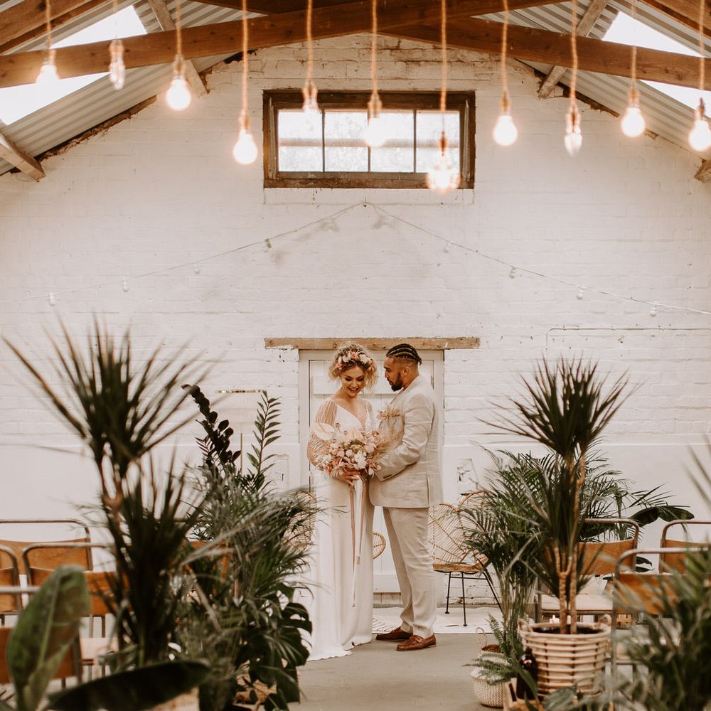 Bride and groom at the altar in industrial style building with tropical plants