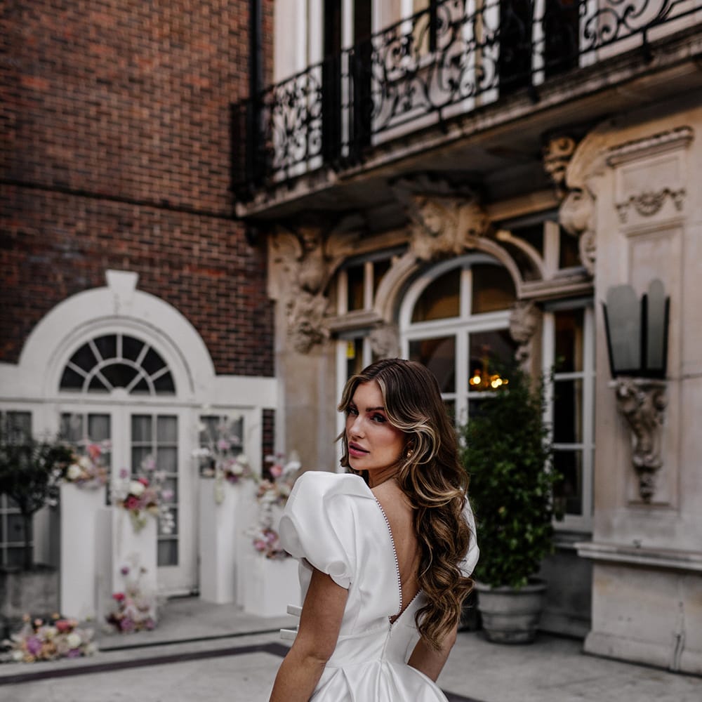 Bride in a Love In Lace Bridal gown with puff sleeves and long wavy hair 