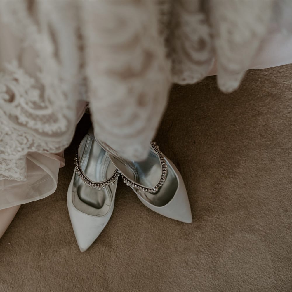 Pointed mint green heels with silver beaded strap next to homemade lace wedding dress for DIY garden wedding