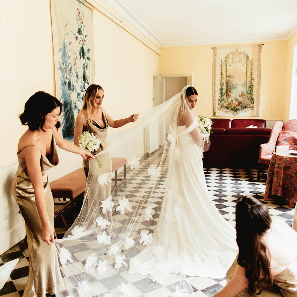 Bride wears Halfpenny London veil complete with floral embellishments as bridesmaids help with veil