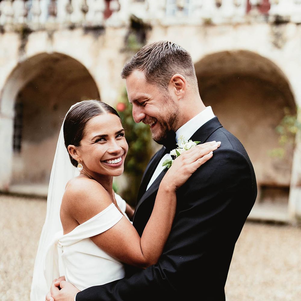 Bride & groom embrace outdoors after wedding ceremony as bride holds her hands on grooms shoulders