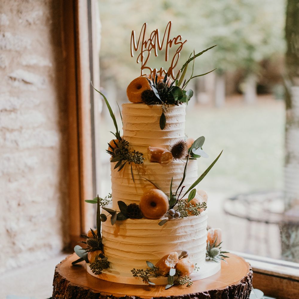 Three tier rustic wedding cake with thistle and doughnut decorations and personalised wedding cake topper