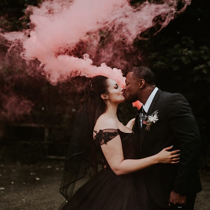 Bride & groom carry pink smoke bomb