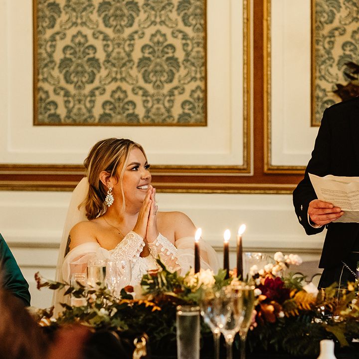 Bride with sparkly earrings puts her hands together for speech 